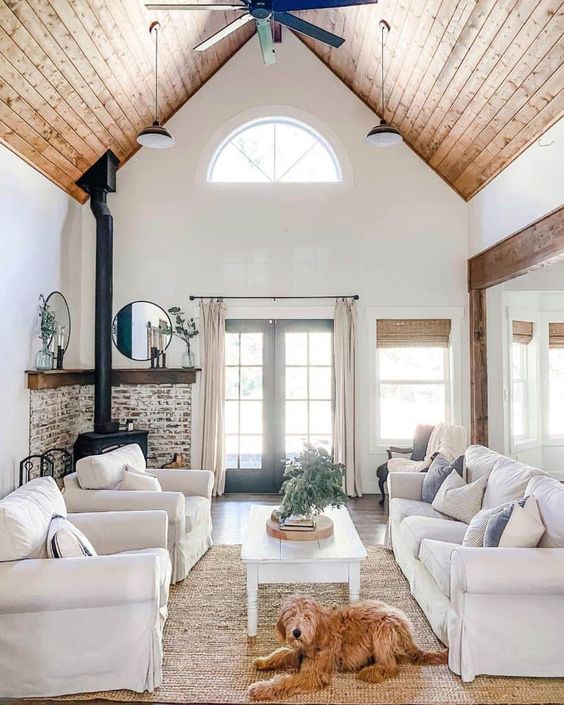 a modern farmhouse living room with a hearth surrounded with brick, white seating furniture, a low coffee table and a jute rug