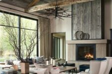 a modern farmhouse living room with reclaimed wood, a fireplace, neutral seating fruniture, coffee tables and an antler chandelier