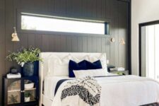 a modern farmhouse meets boho bedroom with a black accent wall, a white bed with neutral bedding, a woven bench, black nightstands