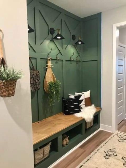 a modern farmhouse mudroom with a green built-in bench and paneled walls, some greenery and pillows