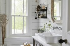 a modern farmhouse powder room with shiplap walls, a grey vanity, a mirror, a sconce and some greenery