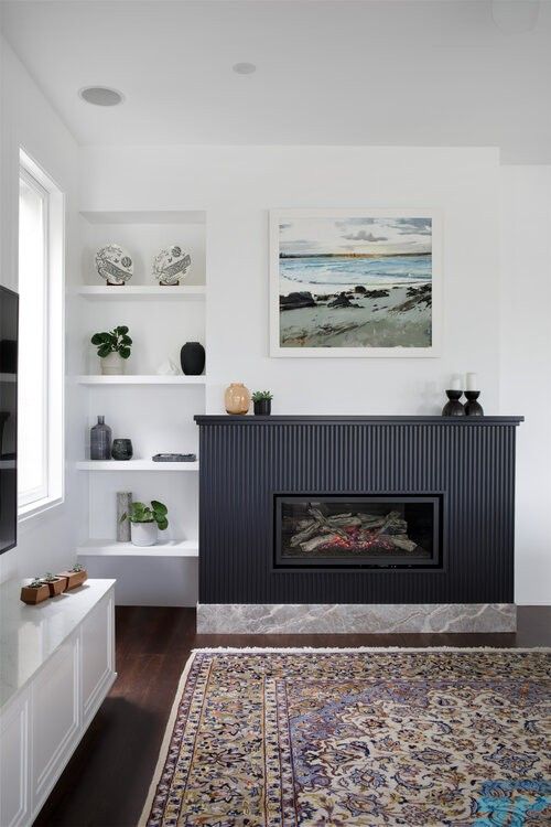 a modern living room with a fireplace with a navy reeded surround, built-in niche shelves and a bold printed rug
