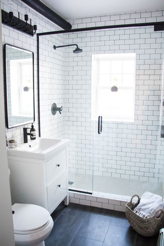 a modern monochromatic bathroom with white subway tiles and black ones, a white vanity and black fixtures here and there