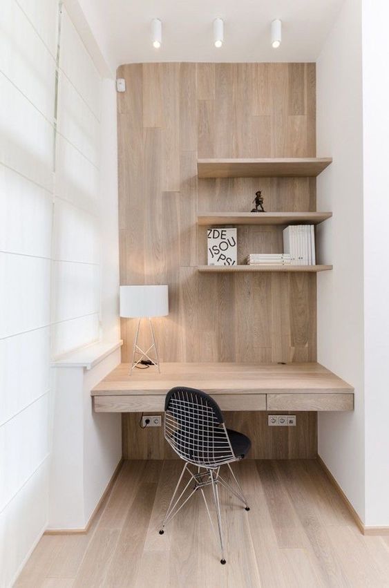 a modern niche clad with laminate, with stained shelves and a desk with drawers, a table lamp and some books is cool