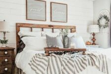 a neutral farmhouse bedroom with shabby wooden furniture, neutral and printed textiles, greenery and cool rustic lamps