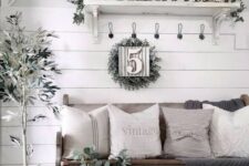 a neutral farmhouse entry with a sign, greenery, potted plants, a wooden bench with neutral textiles