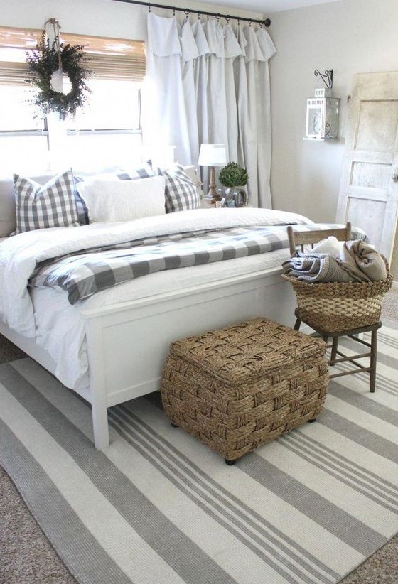 a neutral farmhouse space with a white bed, neutral bedding and buffalo check, baskets for storage and shades and curtains