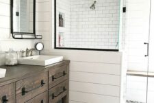 a neutral modern farmhouse bathroom with a shower space, a dark-stained timber vanity, a printed tile floor, black hardware and vintage lamps