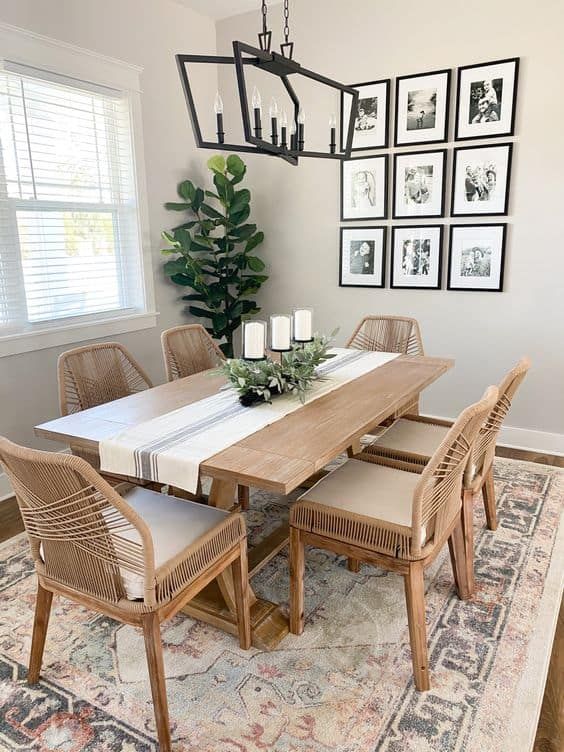 a neutral modern farmhouse dining space with a heavy trestle dining table, wooden chairs, a gallery wall and a pendant lamp