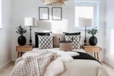 a refined boho farmhouse bedroom with contrasting black and tan bedding, cane nightstands, black vases with greenery and a pendant lamp