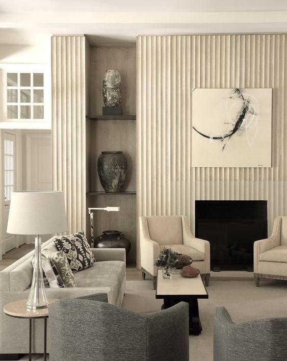 a refined living room with a fireplace and a reeded surround, built-in shelves, neutral and graphite grey furniture, coffee tables