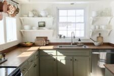a relaxed farmhouse kitchen with white shiplap walls, light green cabinets, butcherblock countertops, wooden beams