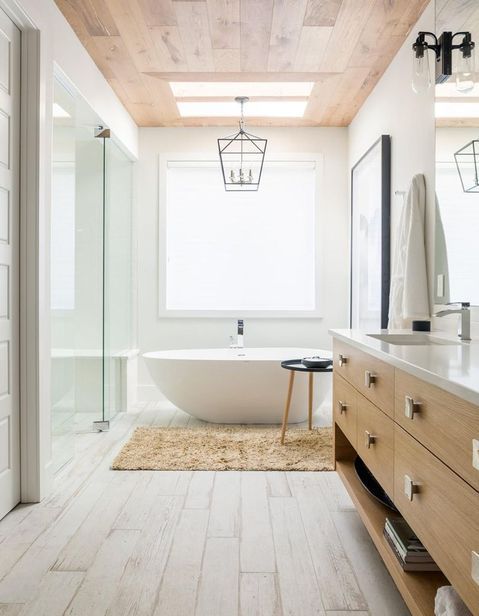 a serene modern farmhouse bathroom with a wooden ceiling, a stained timber vanity, a shower space, an oval tub and a black frame pendant lamp