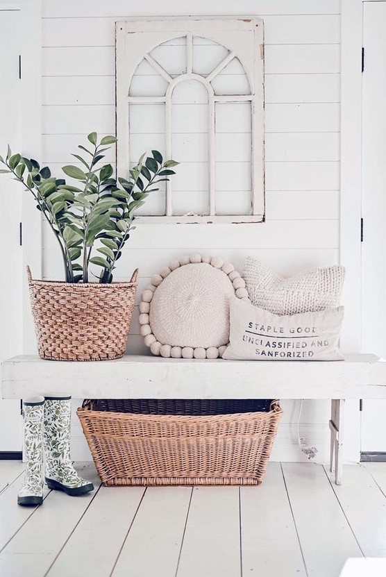 a serene modern farmhouse entryway with a white bench, a vintage window frame, a potted plant and some pillows