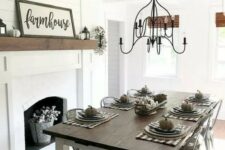 a simple modern farmhouse dining area with a white fireplace, signs and pumpkins, a wooden table and metal chairs