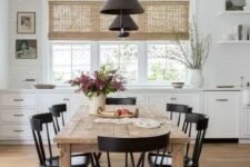 a simple modern farmhouse dining space with a stained wooden table, vintage black chairs, modern black pendant lamps is cool