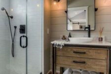a small farmhouse bathroom with neutral tiles, patterned ones on the floor, a wooden vanity and black fixtures here and there