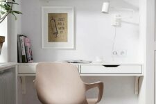 a small yet cool home office nook in the living room created with IKEA items – shelves, a desk and a blush chair plus a white sconce
