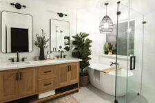 a stylish modern farmhouse bathroom with an oval tub, a double timber vanity, mirrors with black frames, a woven pendant lamp and hex tiles on the floor