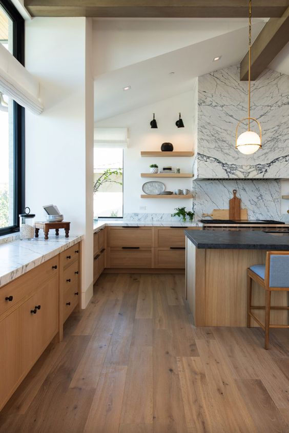 a stylish modern farmhouse kitchen with stained lower cabinets, a large kitchen island, marble countertops and a backsplash