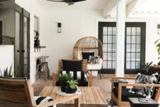 a super elegant modern farmhouse terrace with stained furniture, black and white textiles, an egg chair, a wooden coffee table