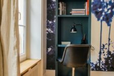 a tiny working nook built into a wall in the living room, with a wall mural and a teal inside, with a black chair