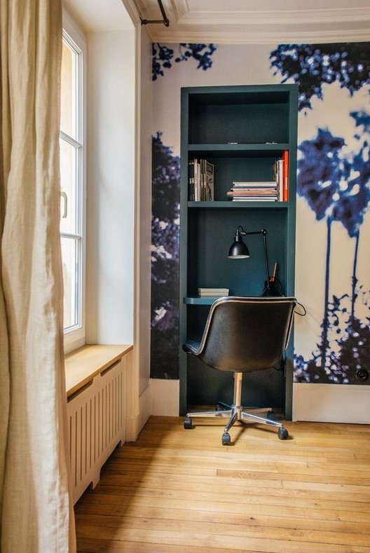 a tiny working nook built into a wall in the living room, with a wall mural and a teal inside, with a black chair