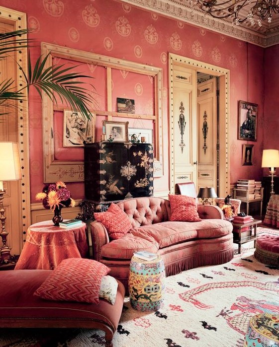 a unique refined living room with pink wallpaper walls, pink furniture, incusted doors, a gallery wall and lots of books