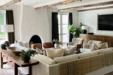 a welcoming Spanish farmhouse living room with a fireplace, a stained sideboard, a neutral sofa, a console table, cozy chairs