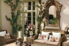 a welcoming rustic patio with wicker and wooden furniture, lot sof vines and a vintage mirror in a wooden frame