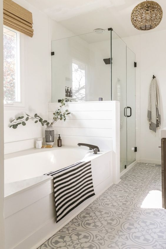 a white modern farmhouse bathroom with a printed tile floor, shiplap wlals, a shower and a tub, a woven pendant lamp and shades