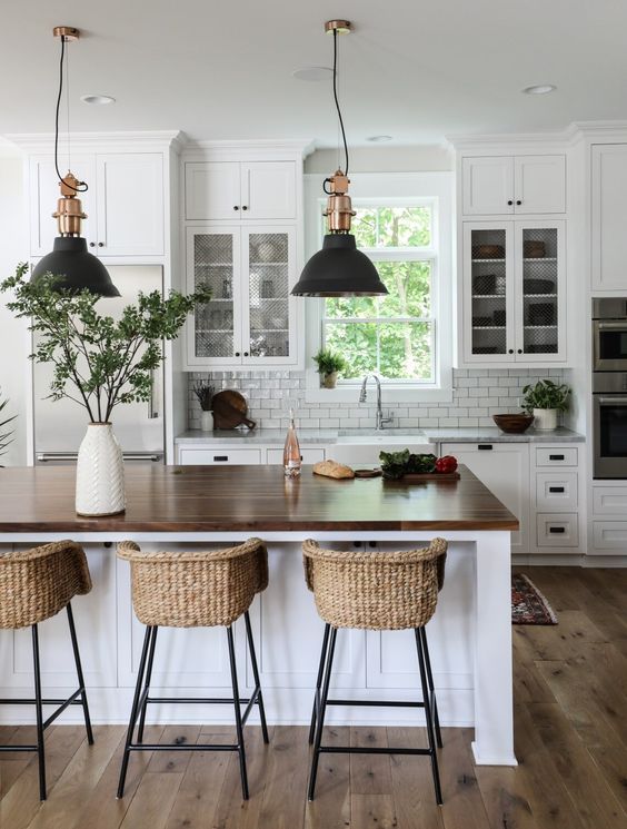 a white modern farmhouse kitchen with shaker cabinets, a white subway tile backsplash, a kitchen island and woven stools