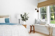 an airy modern farmhouse bedroom with a windowill daybed, a bed with neutral and printed bedding, wooden stools and greenery