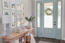 an airy modern farmhouse entry with a console, a grid gallery wall, baskets and pillows, a blue door and a rug