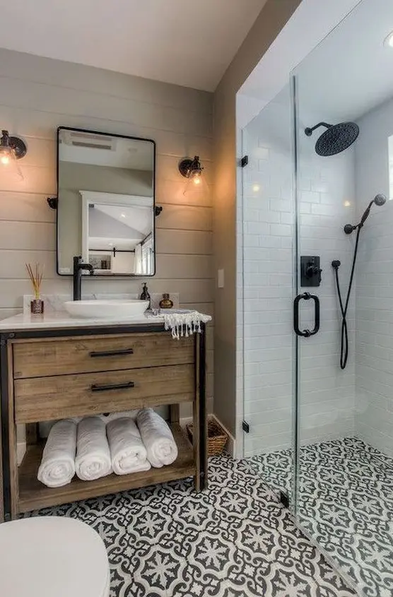 an elegant farmhouse bathroom with black and white mosaic tiles, a wooden vanity and touches of black for drama