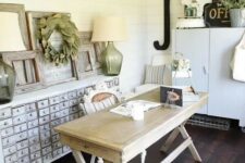 an inspiring home office with white beadboard walls, a wooden desk, a shabby chic storage unit, a black lamp and some decor