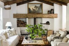 an inviting barn living room with a metal hearth and a wooden mantel, a reclaimed wood ceiling, neutral seating furniture, a printed rug and greenery
