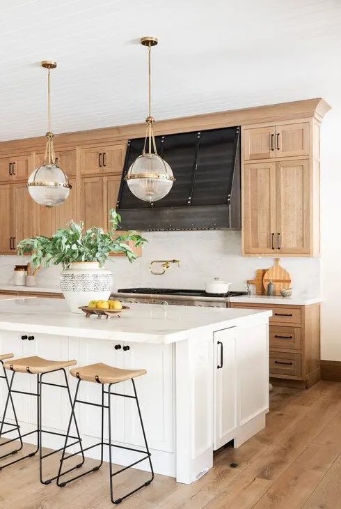 An inviting farmhouse kitchen with light stained shaker style cabinets, white stone countertops and a white backsplash, wooden stools and a white kitchen island