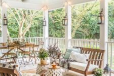 an inviting modern farmhouse terrace with white upholstered furniture, mini side tables, a wooden dining set, some fall decor