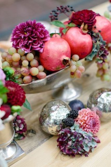a beautiful fall centerpiece of grapes, bold blooms and pomegranates is a catchy idea for your party