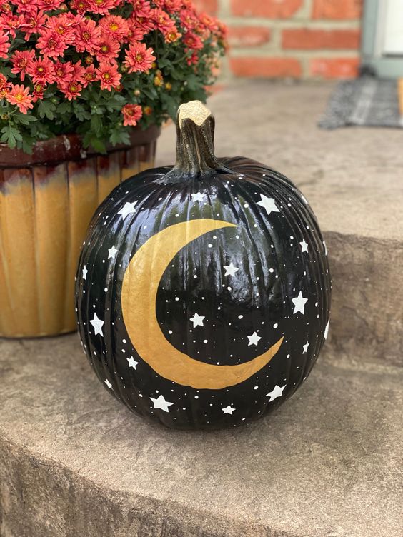 a black Halloween pumpkin with little stars and a gold moon is a great solution for celestial decor