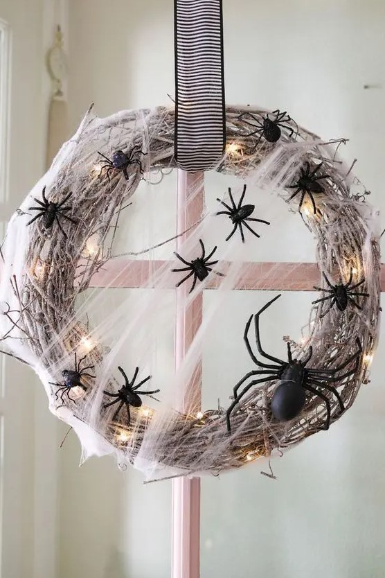 a bold and pretty Halloween wreath of whitewashed vine, LED lights, black spiders and a striped bow is a lovely idea to go for