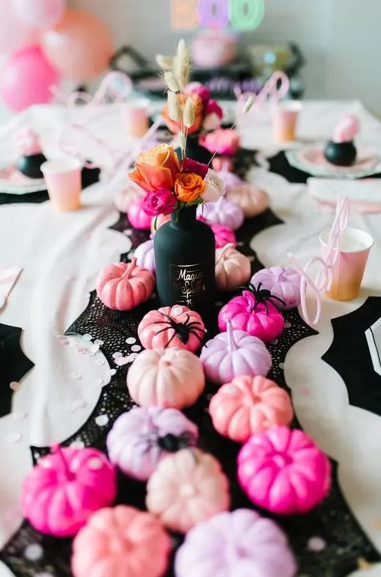super glam Halloween table decor with a black runner, pink, blush, lilac and hot pink pumpkins and bold blooms