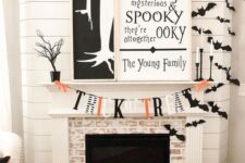 06 an elegant contrasting fireplace with two monochromatic signs, bats, a bright bunting and stacked pumpkins