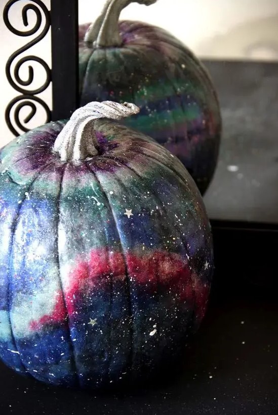 a beautiful blue, pink, grey and purple galaxy pumpkin with little white and silver stars and constellations for Halloween