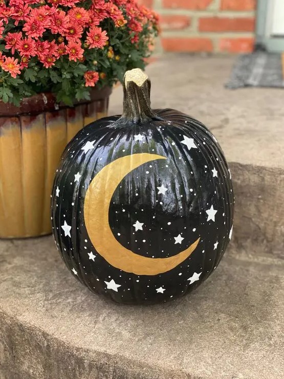 a black Halloween pumpkin with little stars and a gold moon is a great solution for celestial decor