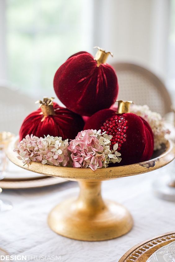 a bright fall or winter centerpiece of a bowl with blush hydrangeas and bold velvet pomegranates with rhinestones is super cool