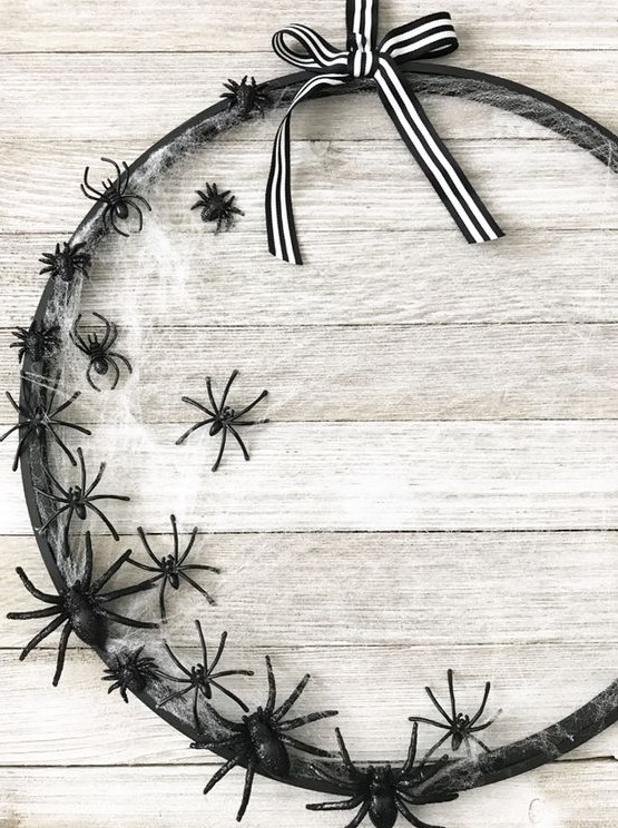 an elegant Halloween wreath of a hoop, with spiderwebs, black spiders and a striped bow on top is a chic solution