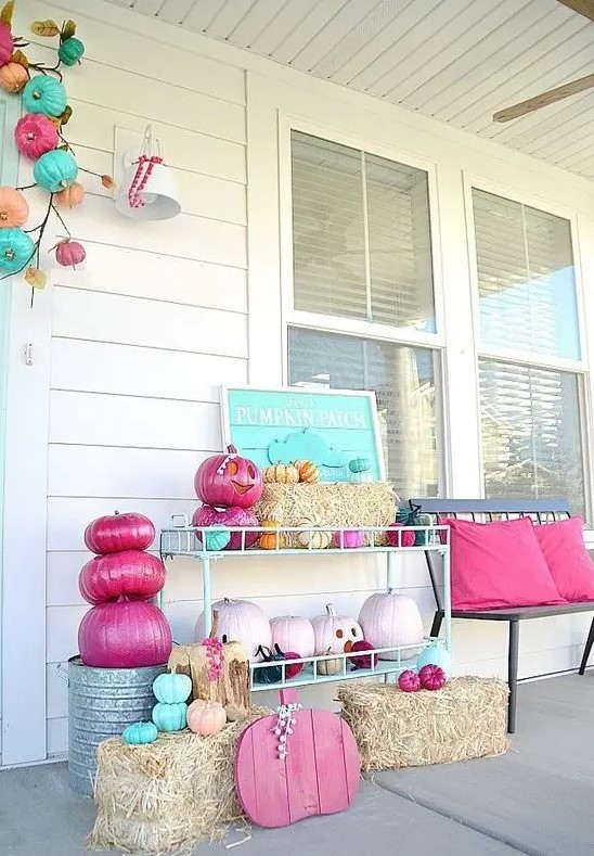 a bright and fun Halloween porch with turquoise, pink, blush pumpkins and signs and pillows