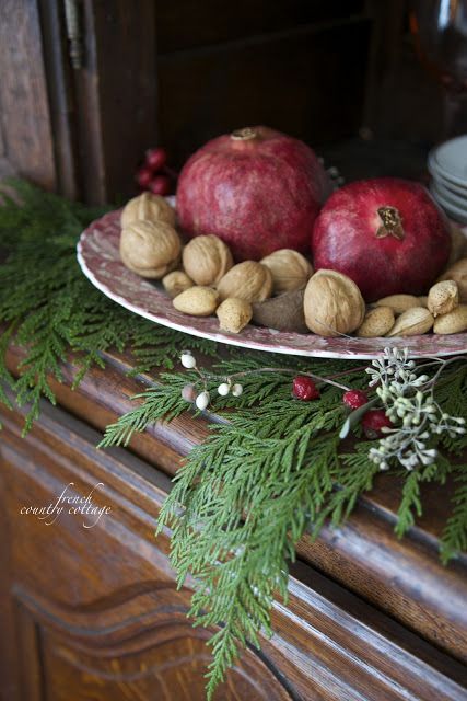 a catchy and simple centerpiece of nuts and pomegranates placed on evergreens is a lovely idea for fall or winter